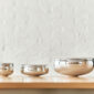 A lifestyle photo of the Puiforcat Selene Collection featuring the 3 sizes of sterling silver bowls on a shelf.