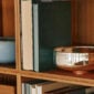 A lifestyle photo of the Puiforcat Selene Collection including sterling silver bowls and vases. A large Selene bowl is pictured on a book shelf.