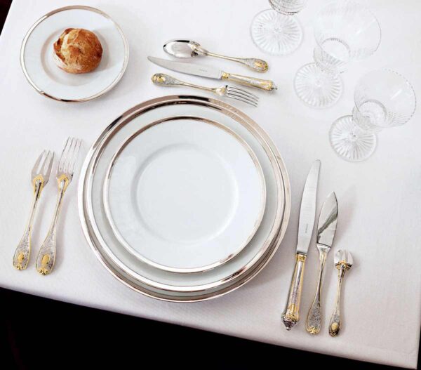A Table Setting with Puiforcat Cercle d’Orfèvre Porcelain Dinnerware with Elysee Sterling Flatware Gold Accents and Saint-Louis Crystal Wine Glass.