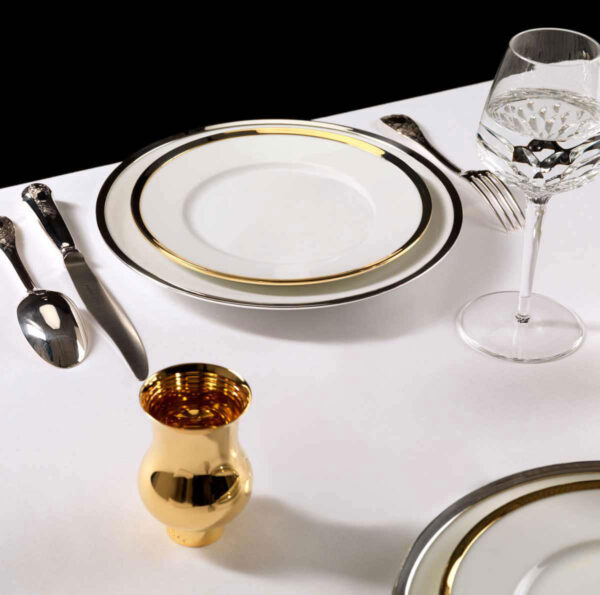A Table Setting with Puiforcat Cercle d’Orfèvre Porcelain Dinnerware with Elysee Flatware and Saint-Louis Folia Crystal Wine Glass. Also shown, Pour le Champagne Cup in Gold Vermeil.