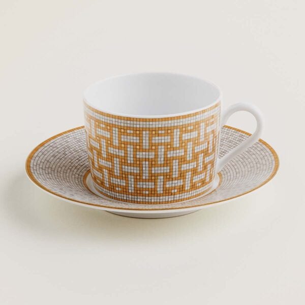 HERMES-DNRWR-Mosaique-au24-Or-026016P-worn-1-1200x1200px-100KB Hermes Mosaique au 24 Gold Tea Cup and Saucer shown on table | Kneen & Co