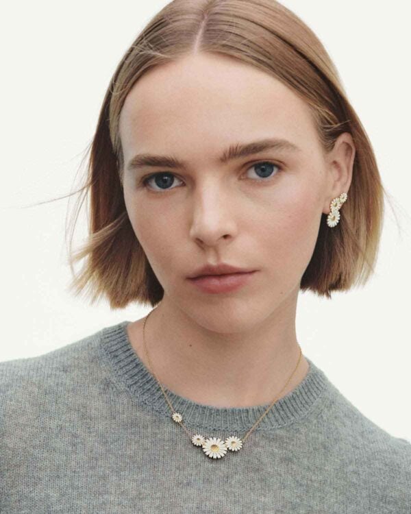 Woman wearing Georg Jensen Daisy Four Flower Necklace in 18 kt plated sterling silver and white enamel | Kneen & Co
