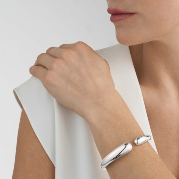Woman wearing Georg Jensen Mercy Hinged Bangle in sterling silver | Kneen & Co
