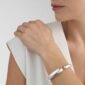 Woman wearing Georg Jensen Mercy Hinged Bangle in sterling silver | Kneen & Co