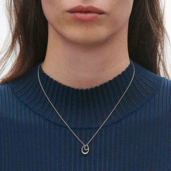 Close up of Woman wearing Georg Jensen Offspring Necklace with Pendant, Small in sterling silver | Kneen & Co
