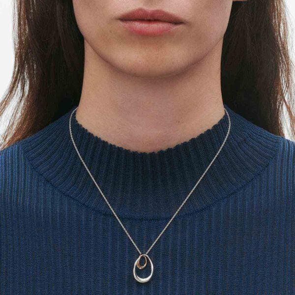 GJ-SS25-ECOM-SHOOT-OFFSPRING-NECKLACE-10012763-Close-up-1200w-100KB Close up of Georg Jensen Offspring Pendant 433B in sterling silver and 18 kt rose gold on model with blue top | Kneen & Co