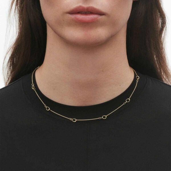 Woman wearing Georg Jensen Offspring Interlinked Necklace, small in 18 kt yellow gold | Kneen & Co