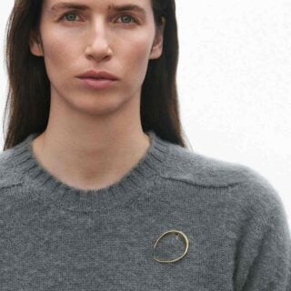 Georg Jensen Offspring Brooch, Small in 18 kt. yellow gold on model | Kneen & Co