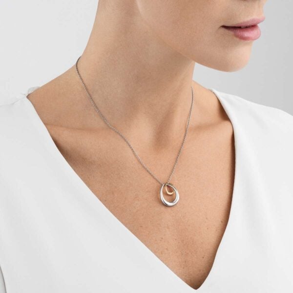 GJensen-10012763-OFFSPRING-PENDANT-WITH-RG-1200w-100KB Georg Jensen Offspring Pendant 433B in sterling silver and 18 kt rose gold on model with white shirt | Kneen & Co