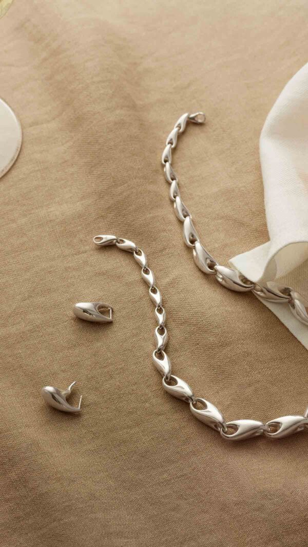 GJ-AW24-Christmas-TACTICAL-JEWELERY-REFLECT-20001095-20001657-20001658-9x16-rev-1200w Georg Jensen Reflect Collection Mood image with jewelry laid out on table | Kneen & Co