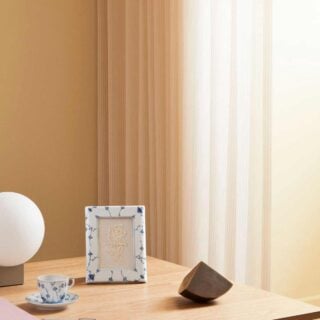 S1_2024_Line_Extensions_Blue_Fluted_Plain_Photo_Frame_16,5×21-cm—10×15-cm_Cup_and_Saucer_17cl_300dpi Royal Copenhagen Blue Fluted Plain picture frame and cup with saucer set on table | Kneen & Co