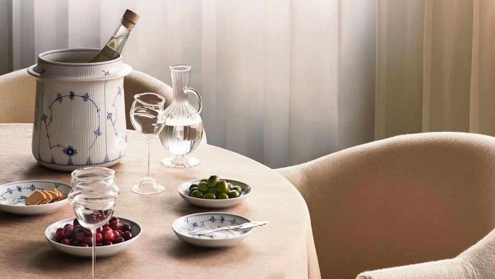 Royal Copenhagen Blue Elements dinnerware styled on a minimalist linen table with crystal glassware, olives, and soft natural light