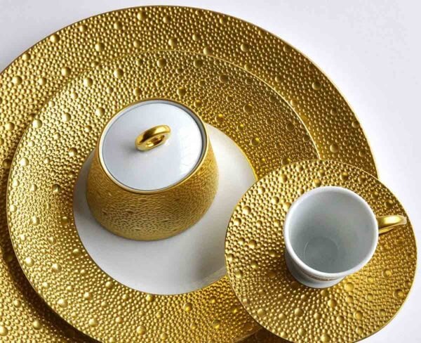 Studio display of Bernardaud Écume Dinnerware in a textured gold and white finish | Kneen & Co