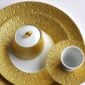 Studio display of Bernardaud Écume Dinnerware in a textured gold and white finish | Kneen & Co