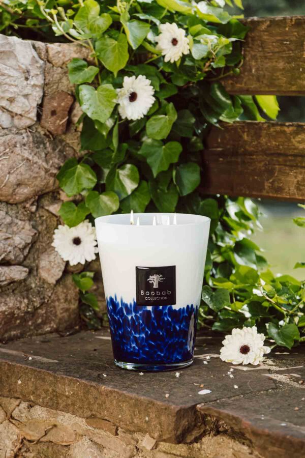 MAX16FT-Feathers-Touareg-Lifestyle-1200w-100KB Baobab Feathers Touareg Scented Candle Max 16 | Kneen & Co lifestyle photo of lit candle with flowers outdoors.