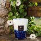 Baobab Feathers Touareg Scented Candle Max 16 | Kneen & Co lifestyle photo of lit candle with flowers outdoors.
