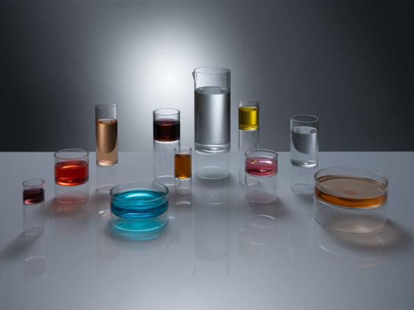 FERRONE-Revolution-Collection-HR-04-Styled-1200w-100KB High-angle studio setting with Fferrone Revolution Glassware in borosilicate glass with multi-colored liquid variants on a reflective surface | Kneen & Co