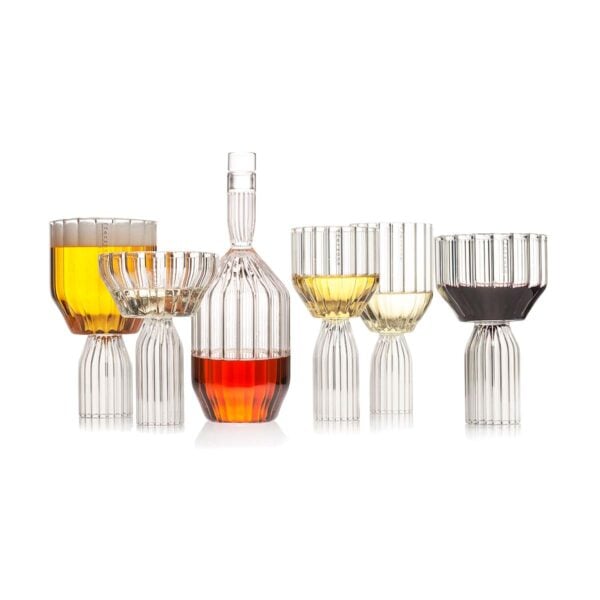 Minimalist studio arrangement of Fferrone Margot Glassware in fluted borosilicate glass featuring an assortment of glasses and a decanter filled with various spirits | Kneen & Co
