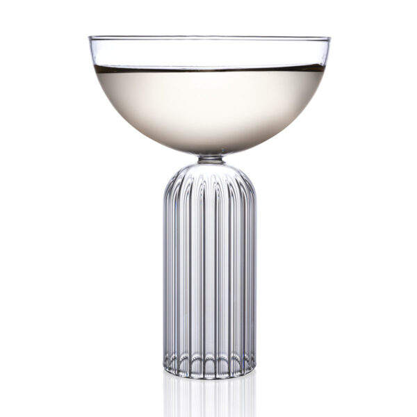 Minimalist studio display of a Fferrone May Coupe in fluted borosilicate glass filled with white wine and featuring a smooth bowl on a ribbed cylindrical base | Kneen & Co
