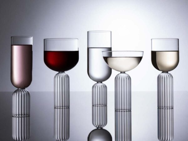 FERRONE-MayGroup-180712-FF-0036-1200w-100KB Elegant studio setting with Fferrone May Glassware in fluted borosilicate glass featuring an assortment of wine, water, and champagne glasses filled with various spirits and reflecting on a dark surface | Kneen & Co