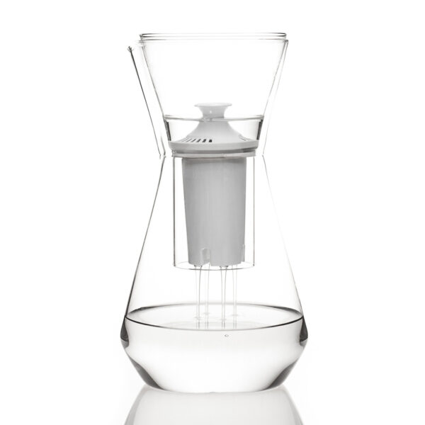 Minimalist studio display of a Fferrone Talise Carafe in clear borosilicate glass featuring a tapered carafe being filled by a matching funnel with a white filter insert |