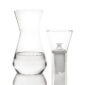 Minimalist studio display of a Fferrone Talise Carafe in clear borosilicate glass featuring a smooth tapered carafe partially filled with water alongside a matching funnel with a white filter insert | Kneen & Co