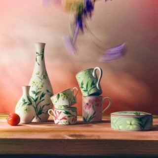 Sunlit rustic table arrangement with Ginori 1735 Florenza vases, mugs, and a round box in fine porcelain featuring various botanical floral patterns and pink accents | Kneen & Co
