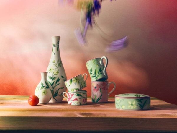 Sunlit rustic table arrangement with Ginori 1735 Florenza vases, mugs, and a round box in fine porcelain featuring various botanical floral patterns and pink accents | Kneen & Co