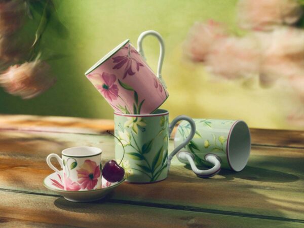 GINORI-FLORENZA-SET-07-0037-1200w-100KB Sun-dappled outdoor wooden table with Ginori 1735 Florenza mugs and coffee cup in fine porcelain featuring pink and green floral patterns with a single cherry | Kneen & Co