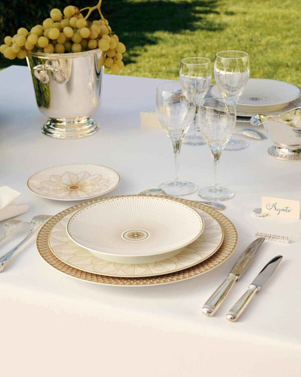 Elegant garden table set with the Christofle Malmaison Impériale collection in fine Limoges porcelain featuring intricate gold-leaf detailing | Kneen & Co
