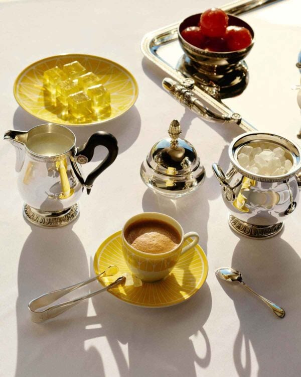Overhead lifestyle shot of a Christofle Malmaison Riviera Coffee Cup and Saucer in yellow Limoges porcelain | Kneen & Co