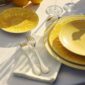 Close-up lifestyle shot of a Christofle Malmaison Riviera place setting in yellow Limoges porcelain | Kneen & Co