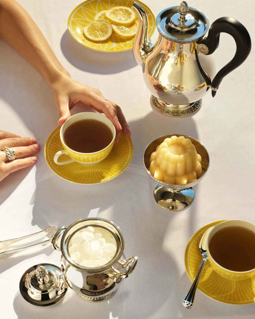 Sun-drenched tea service featuring the Christofle Malmaison Riviera Tea Cup and Saucer in yellow Limoges porcelain paired with silver-plated holloware | Kneen & Co