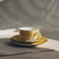 Lifestyle shot of a Christofle Malmaison Riviera Tea Cup and Saucer in yellow Limoges porcelain | Kneen & Co