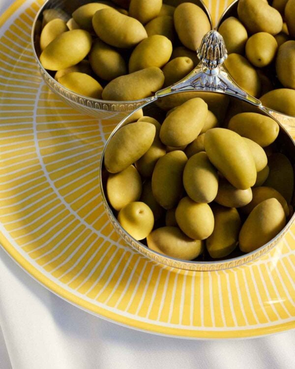 Close-up lifestyle shot of Christofle Malmaison Silver Plated Three-Part Server resting on a Riviera yellow Limoges porcelain plate | Kneen & Co