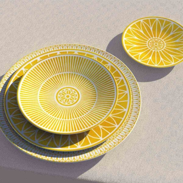 CHRISTOFLE-MALMAISON-RIVIERA-GAMME-2026-RGB-HD-12-1200w-100KB Perspective lifestyle shot of a stacked Christofle Malmaison Riviera dinnerware in yellow Limoges porcelain showcasing various hand-drawn geometric and lotus leaf patterns | Kneen & Co