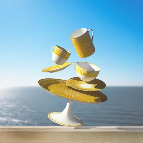 CHRISTOFLE-MALMAISON-RIVIERA-GAMME-2026-RGB-HD-15-1200w-100KB Surrealist lifestyle composition of floating Christofle Malmaison Riviera cups and plates in yellow Limoges porcelain | Kneen & Co