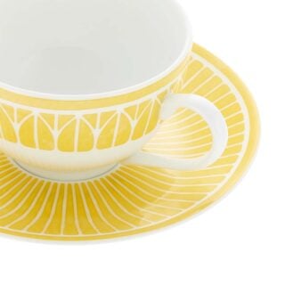 Close-up shot of Christofle Malmaison Riviera Tea Cup and Saucer in yellow Limoges porcelain with hand-drawn palmette detailing | Kneen & Co