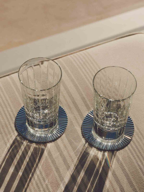 Sunlit casual lifestyle setting featuring Christofle Malmaison crystal tumblers showcasing deep vertical light-refracting cuts | Kneen & Co
