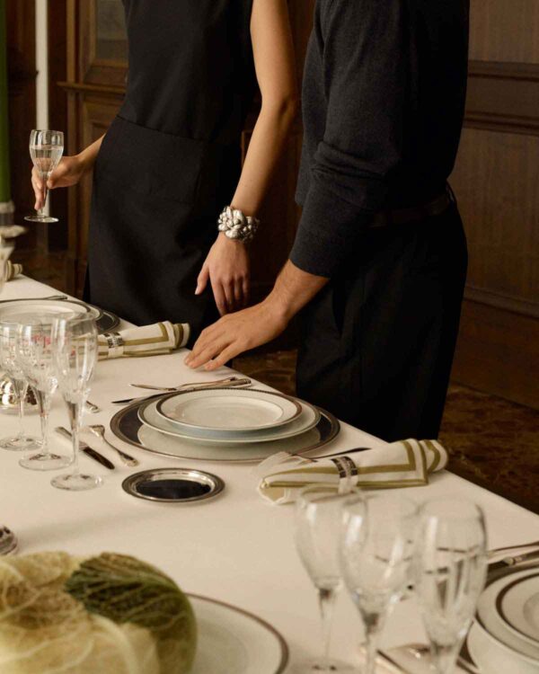 CHRISTOFLE-NewMalmaison-Mood-2026-RGB-HD-4-1200w-100KB Sophisticated evening dinner party setting featuring Christofle Malmaison porcelain plates highlighting refined platinum borders | Kneen & Co
