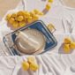 Sunlit picnic setting featuring a Christofle Malmaison Impériale porcelain plate and silver-plated tray highlighting intricate gold lotus patterns and mirror-polished flatware on draped white linen | Kneen & Co