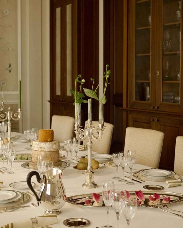 CHRISTOFLE-NewMalmaison-Mood-2026-RGB-HD-7-1200w-100KB Stately formal dining setting featuring Christofle Malmaison showcasing mirror-polished silver finishes and neoclassical leaf engravings on a layered tablescape | Kneen & Co