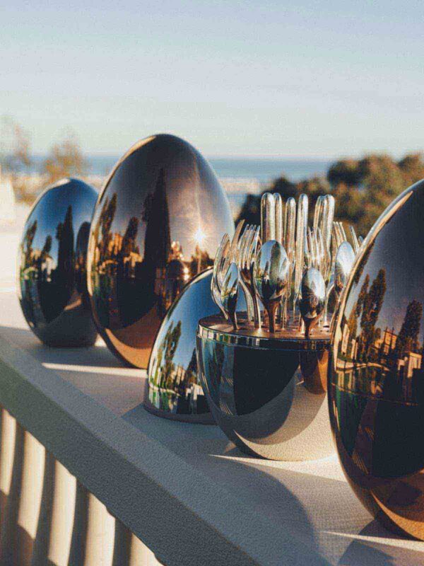 Scenic outdoor setting of the Christofle Mood Flatware Set in an egg-shaped storage | Kneen & Co