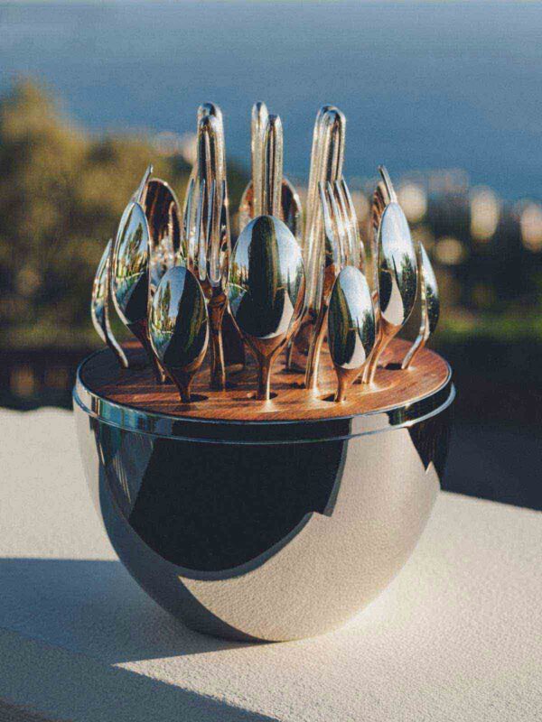Close-up shot of the Christofle Mood Flatware Set featuring silver-plated cutlery arranged in a walnut wood disk | Kneen & Co