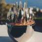 Close-up shot of the Christofle Mood Flatware Set featuring silver-plated cutlery arranged in a walnut wood disk | Kneen & Co