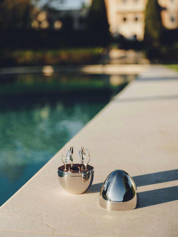 Scenic outdoor setting of the Christofle Mood Flatware Set in an egg-shaped storage | Kneen & Co