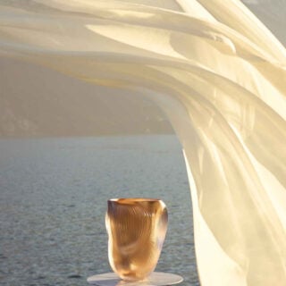Lalique Alizé Large Vase with Pink Gold Leaves set on table with ocean backdrop | Kneen & Co