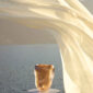 Lalique Alizé Large Vase with Pink Gold Leaves set on table with ocean backdrop | Kneen & Co