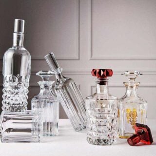 Baccarat crystal decanters from the Harcourt 1841, Harmonie, and Louxor collections displayed together on a refined tabletop, showcasing handcrafted French crystal, architectural silhouettes, and signature cut patterns. | Kneen & Co.