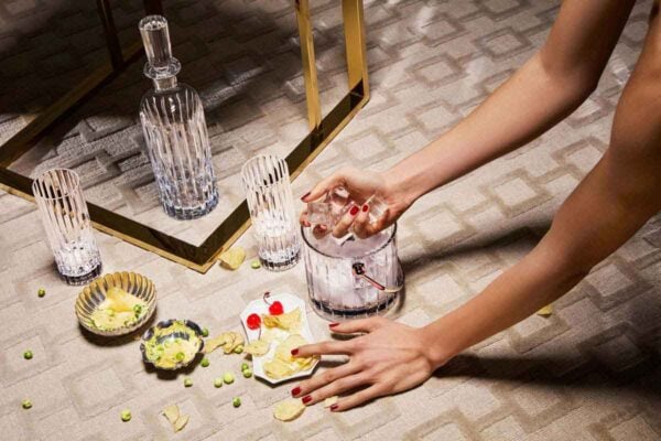BACCARAT-1703341-1894083-2816795-lifestyle-1200w-100KB Baccarat Harmonie crystal barware, including a whiskey decanter, highball glasses, and ice bucket, arranged for cocktail service with ice and appetizers, showcasing the collection's signature fluting and contemporary French crystal craftsmanship | Kneen & Co